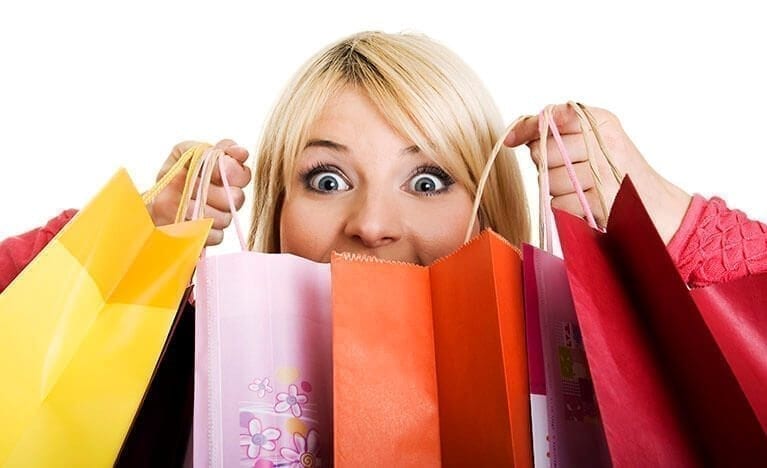 Woman Holding Several Different Colored Shopping Bags In Front of Face