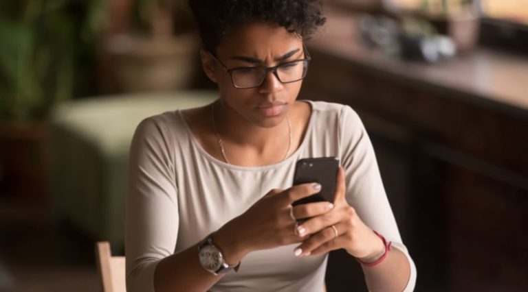 young african american woman looking at phone with a confused expression